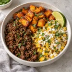Bowl of seasoned ground beef, roasted sweet potato cubes and creamy charred corn with cotija and lime.