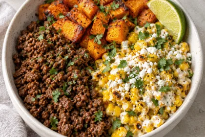 Bowl of seasoned ground beef, roasted sweet potato cubes and creamy charred corn with cotija and lime.